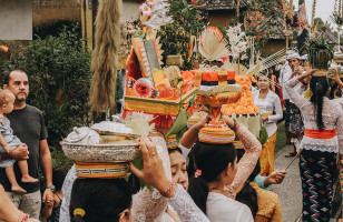 Bali people holding fruit on top of their heads parading down a road celebrating the day of silence.