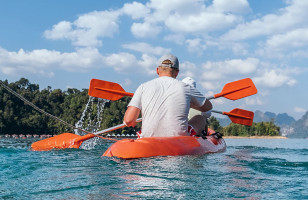 Topdeck travel group kayaking in a line across Cheow Lan lake in Thailand.