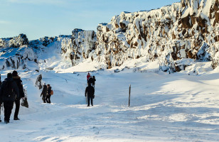 Topdeck tour group trekking across the snowy fields of Thingvellir National Park in Iceland.