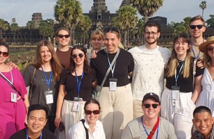 Topdeck tour group posing for a photo in front of the famous Angkor Wat temple in Cambodia, known for being the largest religious structure in the world.