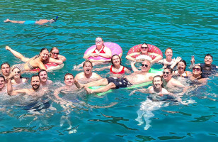 Topdeck tour group posing for a photo while swimming in the crystal blue waters of Turkey.