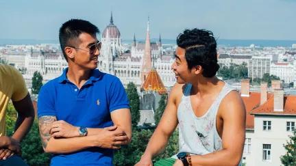A group of Topdeck travelers chatting with each other in Budapest, with the Hungarian Parliament in the background.