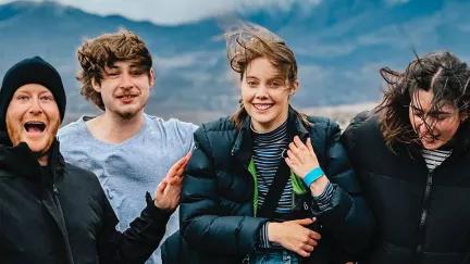 Topdeck travellers taking a group photo during their New Zealand trip, with Mount Sunday in the background.