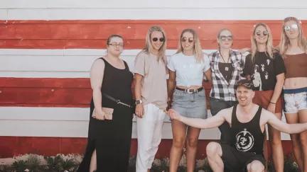 People from a Topdeck tour across the USA posing in front of the Stars and Stripes for a photo.