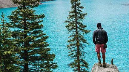 A Topdeck traveler, looking out over the clear blue waters of Canada's Morraine Lake.
