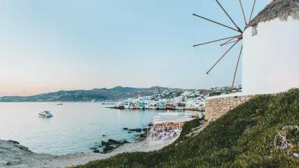 A view of the coast of Mykonos, with a beachside restaurant in the foreground.