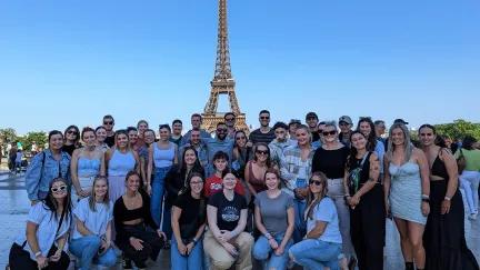 Topdeck tour group taking a photo together in front of the famous Eiffel Tower of Paris during their Get Social: Mega European trip.