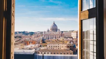 A view of the grand Vatican City through an open window during a sunny day.