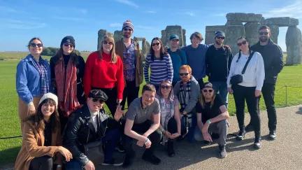 Topdeck travellers taking a group photo in front of the iconic Stonehenge landmark.