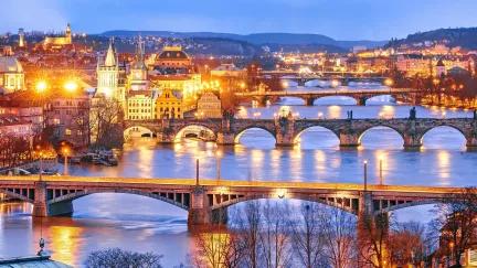 A view of the bridges leading out of Prague, lit up at night during winter.