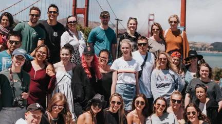 Topdeck travelers posing together for a group photo in front of the iconic Golden Gate Bridge in San Francisco.