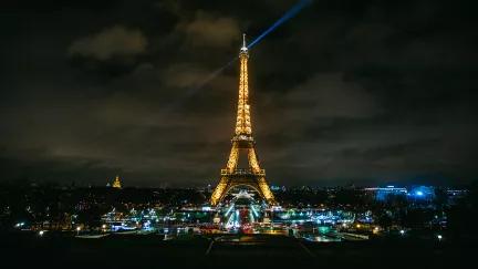 A view of the Eiffel Tower at night, it's lights shining like a beacon across the Paris skyline.