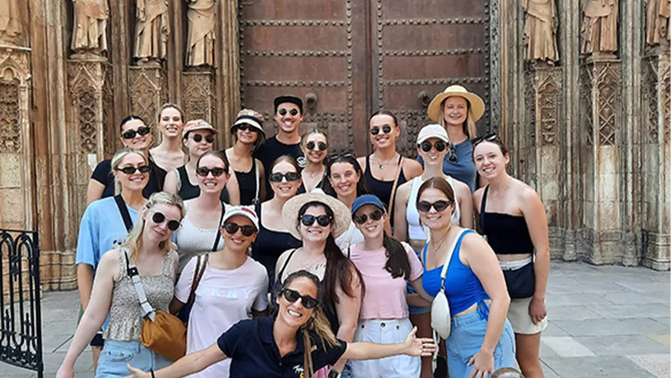 Topdeck travelers taking a group photo together in front of a set of old cathedral doors.