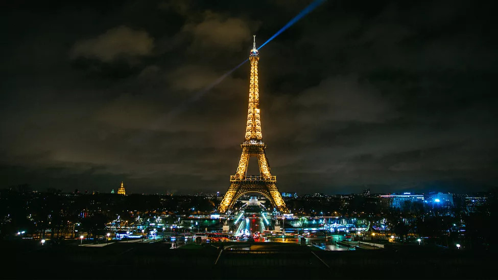 A view of the Eiffel Tower at night, it's lights shining like a beacon across the Paris skyline.