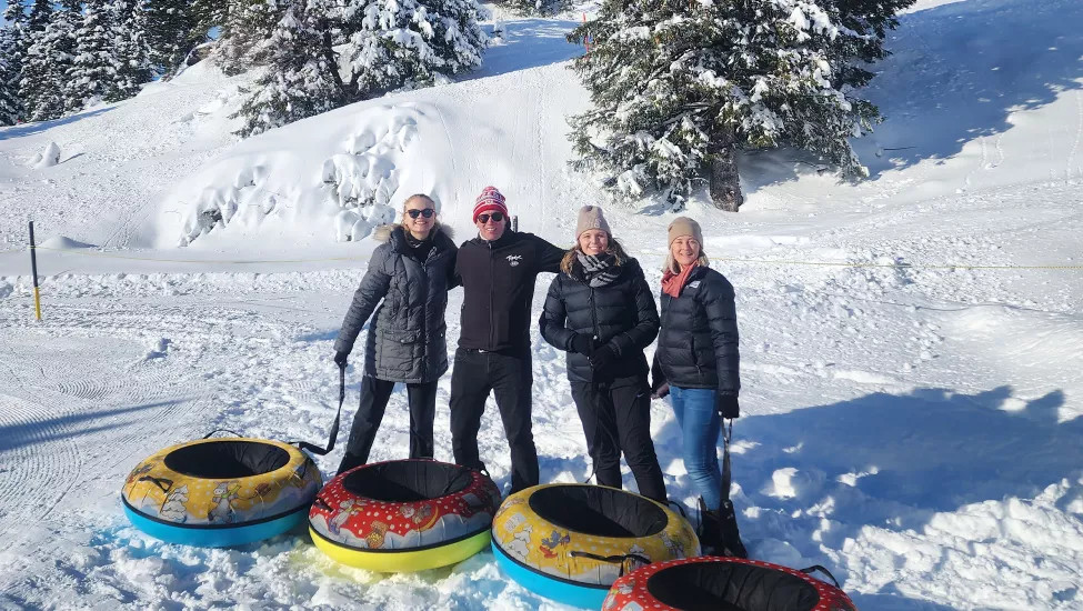 Four Topdeck travelers posing together before going inner tube sledding at the Swiss Alps.