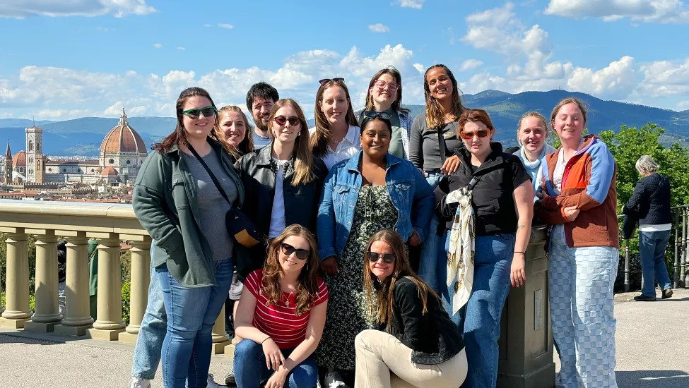 Small group of people posing together for a photo with a view of Florence behind them.