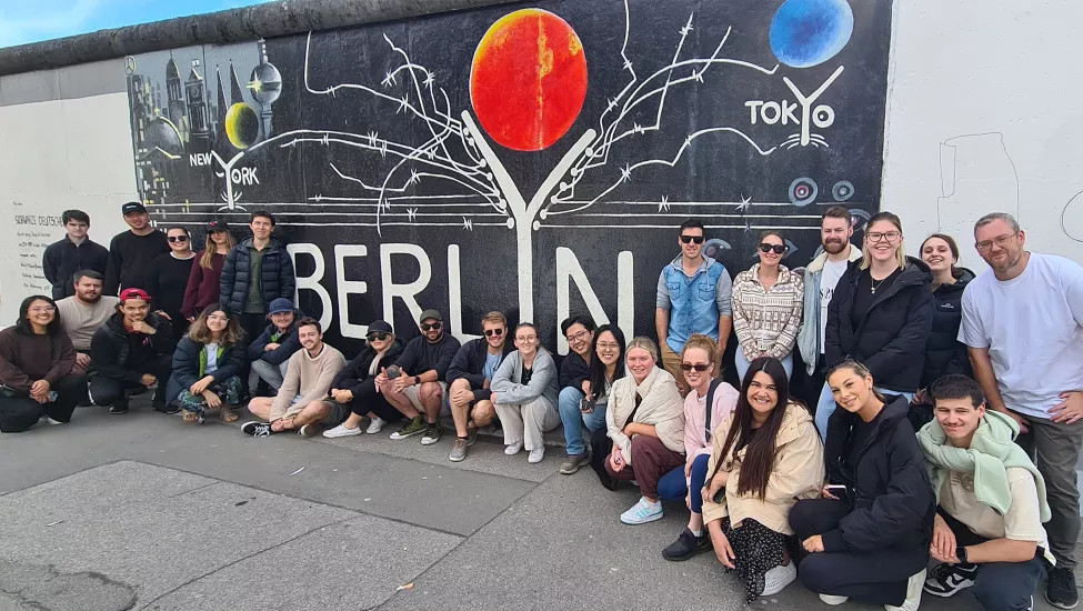  Topdeck travel group posing for a photo in front of the Berlin Postcard mural.