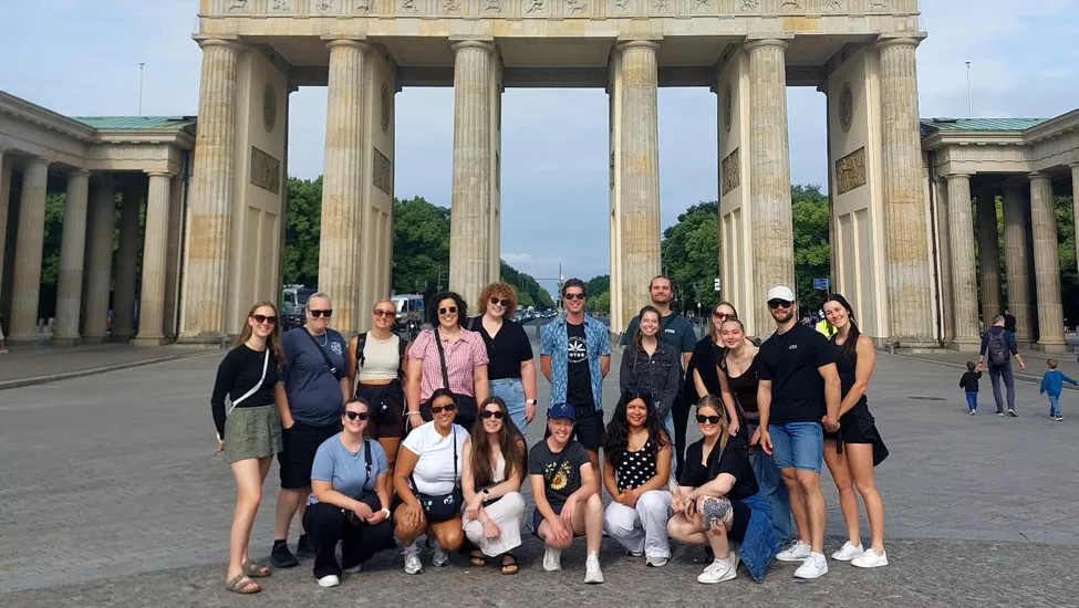 Group of people standing in front of the Brandenburg Gate in Berlin.