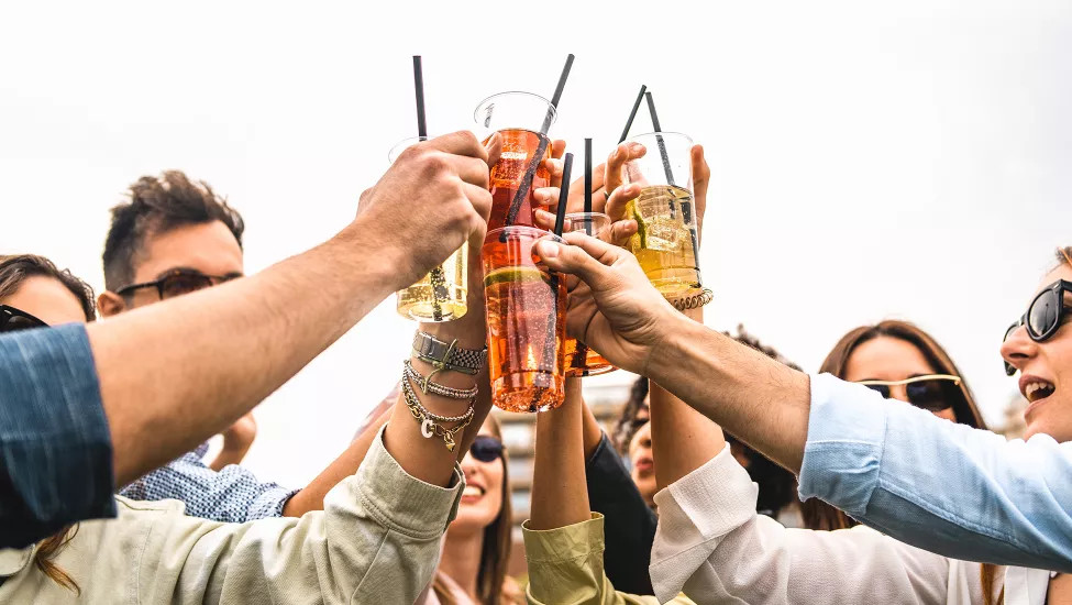People wearing sunglasses while holding their drinks together in a positive gesture.