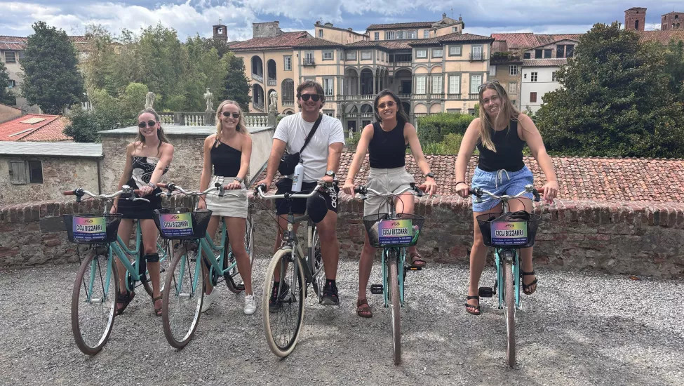 Five people stand together on bikes wearing sunglasses in Italy.