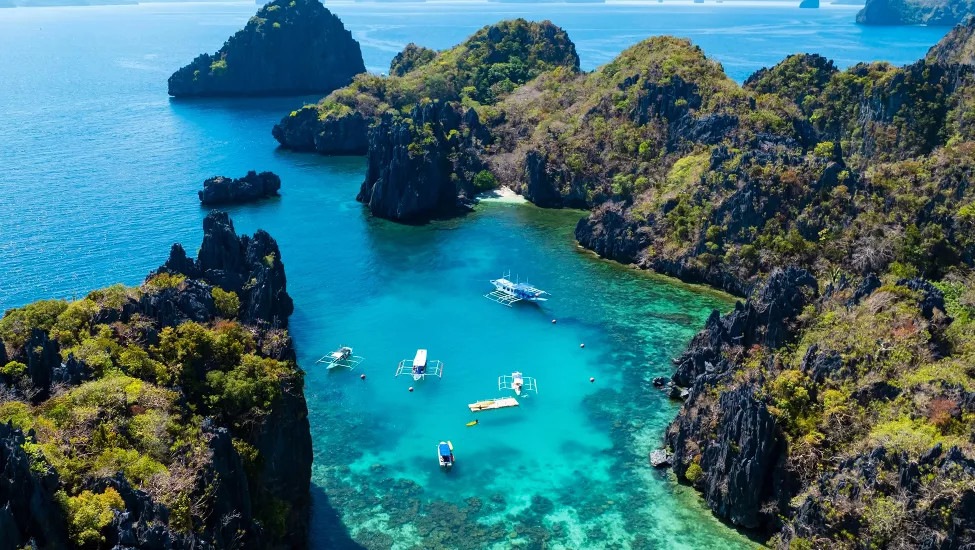 View of boat floating along the coastline in the blue waters of El Nido.