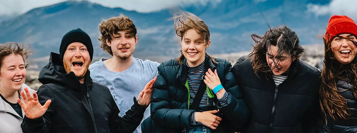 Topdeck travellers taking a group photo during their New Zealand trip, with Mount Sunday in the background.