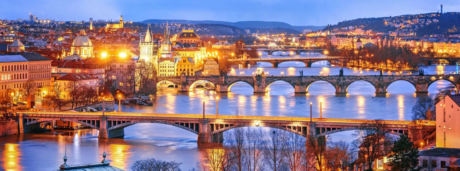 A view of the bridges leading out of Prague, lit up at night during winter.