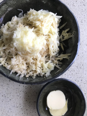 All the ingredients in a black bowl and a side bowl of butter