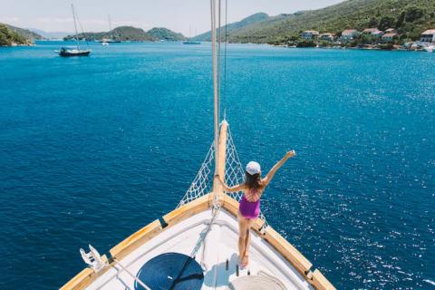 A woman standing at the end of a sailing boat on the Mediterranean Sea