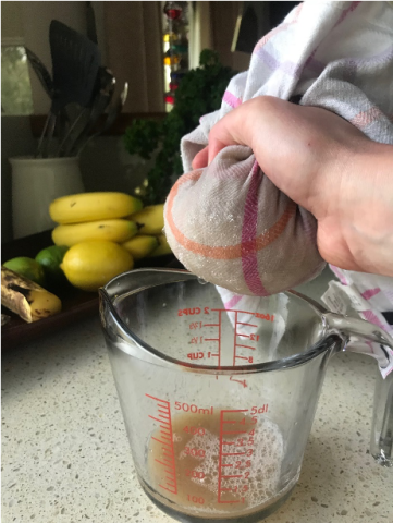 Ingredients in a cloth being squeezed, with the juices being caught in a measuring jug below