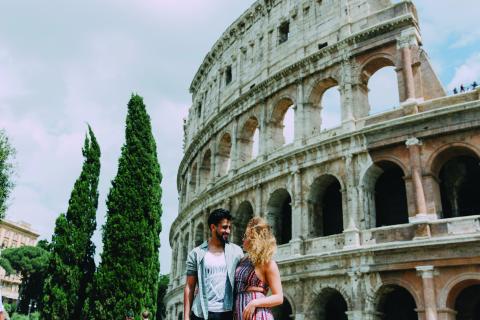 A romantic couple standing in front of the Colosseum 
