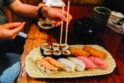 A person using chopsticks to eat their dish of sushi