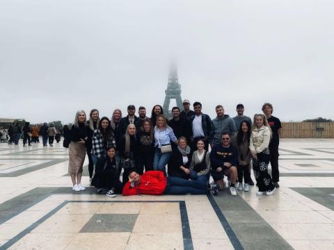 Topdeckers pose in front of the Eiffel Tower, but the top of it disappears into fog