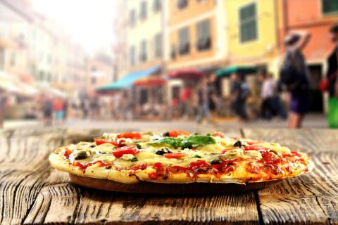 A pizza on a wooden table outside 