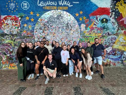 a group of topdeckers in front of the Lennon Wall in Prague
