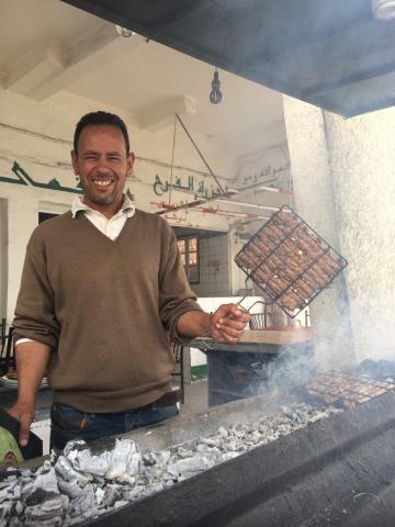 A man grilling Kefta (meatballs) 