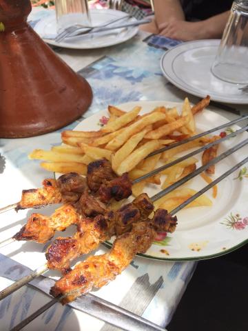 a plate of shish kebab on skewers and chips