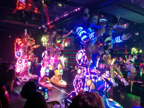 Robots with light strips on them dancing in a bar in Japan