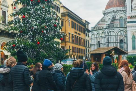 People taking a walking tour with a tour guide next to a Christmas tree