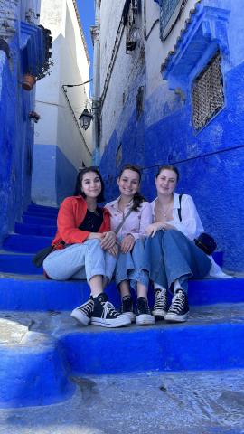 Three women sitting on blue steps