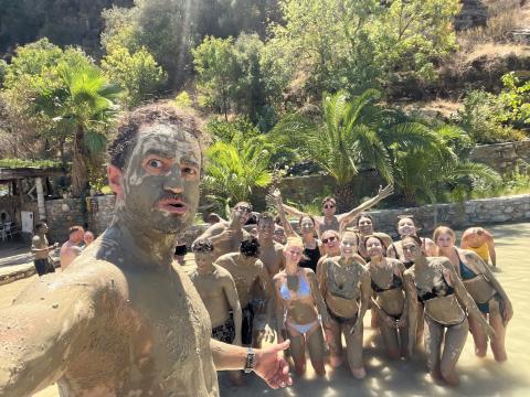 selfie of a group of people covering in mud in a lake