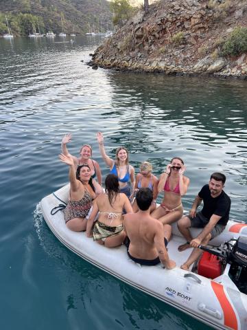 Group of people waving and smiling on a motor boat