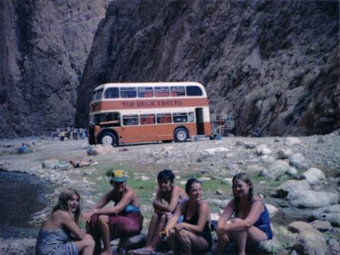 People sitting on rocks, with the Topdeck bus in the back