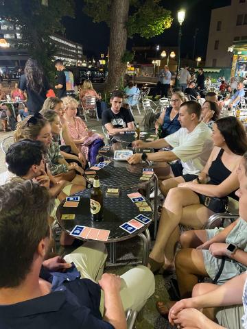 A group of topdeckers sitting on tables outside playing cards