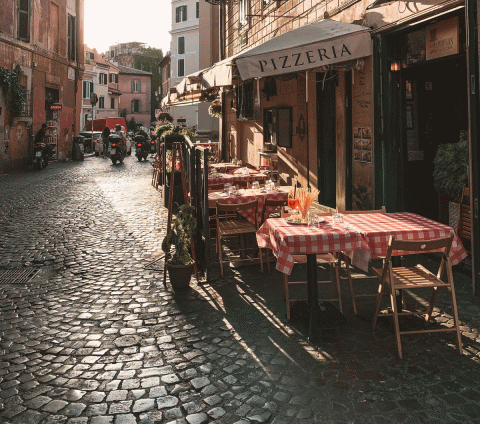 Tables outside on a cobbled street for a Pizzeria