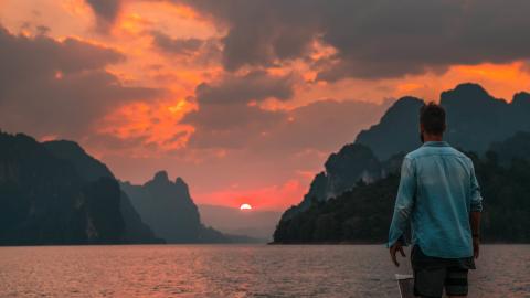 A person standing looking out to sea while the sunsets