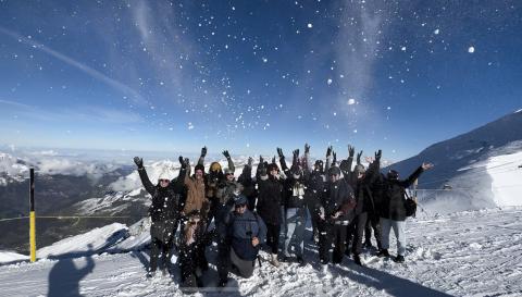 Topdeckers throwing their arms in the air in the snow