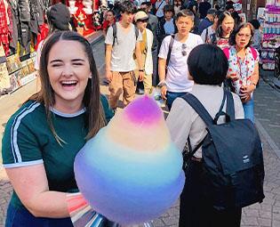 A woman holding a large rainbow candy floss