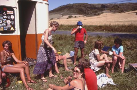 People sitting on the grass outside a Topdeck bus