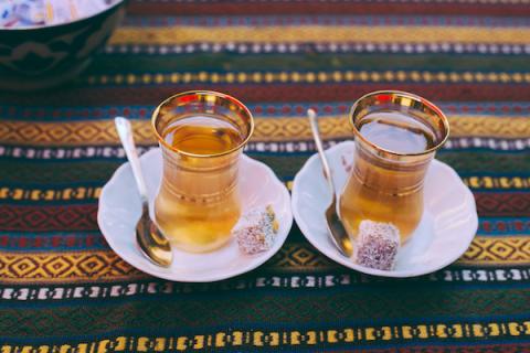 Two small glasses of cay (Turkish tea) on small plates with a spoon